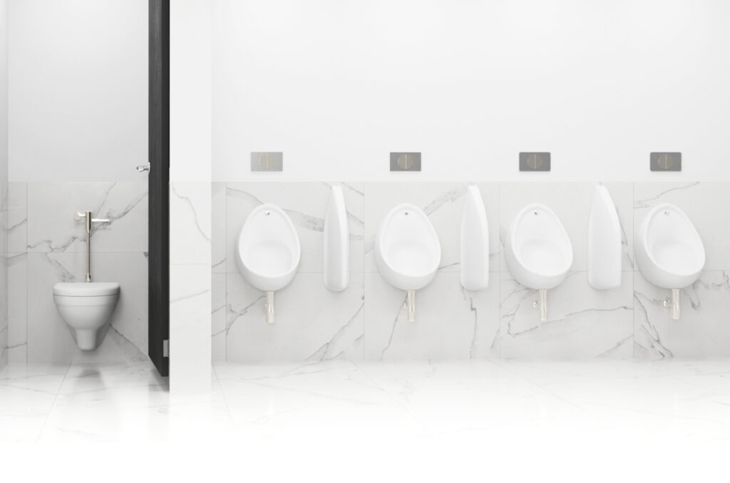 Row of white wall-hung school urinals with privacy dividers and flush plates in a clean, modern restroom, with a WC cubicle on the left — Lecico durable range.